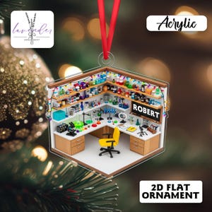 May include: Acrylic 2D flat ornament shaped like a laboratory. The ornament features a detailed interior with lab equipment, shelves of colorful bottles, and a yellow chair. The name "ROBERT" is displayed on a sign.