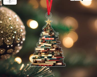 May include: Acrylic Christmas tree ornament made of stacked books, adorned with a gold star and red ribbon. The ornament features a festive design with red, green, and gold accents, perfect for holiday decor.