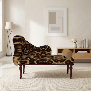 May include: A chaise lounge with a leopard print pattern. The chaise has a curved back and armrest, with dark wood legs. The upholstery is brown and tan, with a spotted design. The chaise is placed on a white rug.