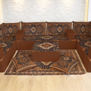 May include: A large, U-shaped seating arrangement with a matching coffee table and rug. The furniture features a brown base with patterned upholstery in shades of brown, black, and gold. The rug and cushions complement the sofa's design.