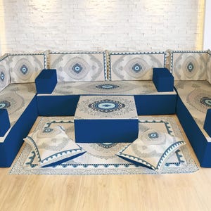 May include: A modular sofa set with a blue base and patterned cushions. The cushions and rug feature a circular design in shades of blue and cream. Includes a coffee table and throw pillows.