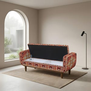 May include: A storage bench featuring a vibrant red, orange, and cream patterned fabric upholstery. The bench has a hinged seat that opens to reveal a white interior storage compartment, supported by four dark wooden legs with a tapered design.