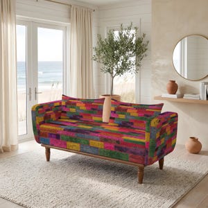 May include: A sofa upholstered in a vibrant, multi-colored fabric featuring a rectangular block pattern in shades of red, yellow, blue, green, and purple. The piece is supported by four tapered wooden legs and features a structured back and armrests.