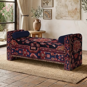 Può includere: Una panca rettangolare rivestita in tessuto blu scuro con un motivo geometrico multicolore nelle tonalità del rosso, rosa e crema. La panca include due cuscini cilindrici abbinati posizionati a ciascuna estremità della seduta.