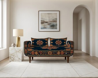 May include: A loveseat featuring a dark navy blue fabric upholstery with an intricate, symmetrical floral pattern in shades of orange, gold, and cream. The piece is supported by four dark brown wooden legs and includes two matching rectangular cushions.