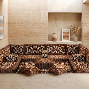May include: A modular brown sofa set with patterned cushions and a matching coffee table. The cushions and table feature a geometric design in shades of brown and cream. The set is arranged on a light-colored floor, creating a cozy seating area.