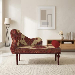 May include: A chaise lounge with a patterned design in red, beige, and brown. The chaise has a curved back and rests on four dark wooden legs. A red, oval-shaped pillow sits on the seat.