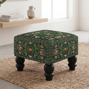 May include: A square ottoman featuring a dark green fabric upholstery with a repeating pattern of orange and pink flowers, green leaves, and small birds. The piece is supported by four black, rounded, turned wooden legs in a classic style.