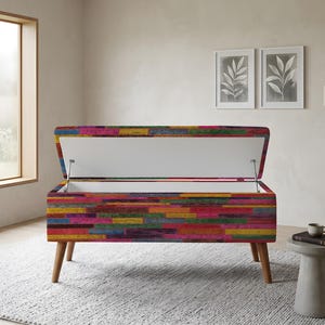 May include: A rectangular storage bench with a vibrant, multi-colored horizontal plank pattern in shades of pink, yellow, blue, and green. The bench features a hinged lid that opens to reveal a white interior and stands on four tapered wooden legs.