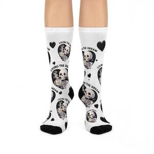以下が含まれることがあります： 白地に黒と白のスケルトン柄と「Living the Dream」の文字が書かれた靴下2足です。