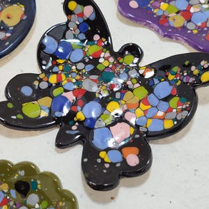 May include: A black butterfly-shaped dish with a colorful confetti design. The dish is made of ceramic and has a glossy finish.
