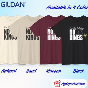 Puede incluir: Cuatro camisetas de manga corta Gildan en colores natural, arena, granate y negro. Cada camiseta presenta el texto "Even My Cat Says NO KINGS" en fuente blanca o negra, acompa&ntilde;ado de un peque&ntilde;o gr&aacute;fico de un gato negro y una corona dorada.