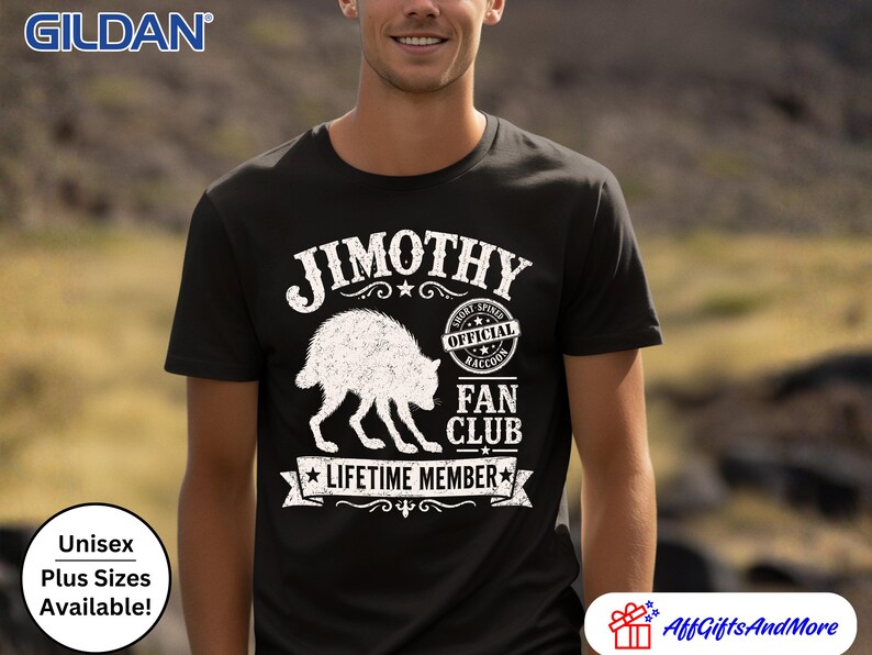 May include: A black short-sleeved t-shirt featuring a white graphic of a raccoon. The text reads JIMOTHY, OFFICIAL SHORT-SPINED RACCOON FAN CLUB, and LIFETIME MEMBER. The design includes a circular stamp and a banner element on the front chest.