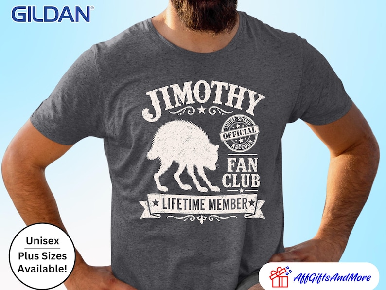 May include: A dark heather grey short-sleeve t-shirt featuring a white graphic of a raccoon. The text reads JIMOTHY, OFFICIAL SHORT-SPINED RACCOON FAN CLUB, and LIFETIME MEMBER. The Gildan brand logo is visible in the top left corner of the image.