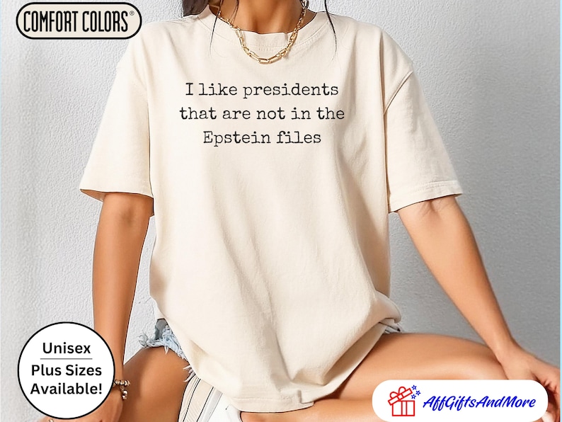 K&ouml;nnte beinhalten: Beiges Comfort Colors T-Shirt mit dem schwarzen Text "I like presidents that are not in the Epstein files". Das Shirt ist unisex und in &Uuml;bergr&ouml;&szlig;en erh&auml;ltlich.