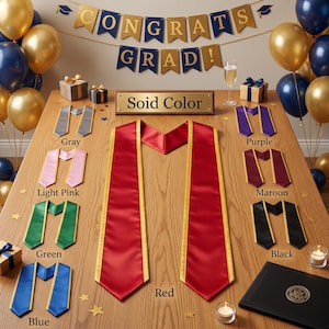 May include: A selection of graduation stoles in colours such as red, blue, and green, with gold edging, are arranged on a wooden table. A banner reading "CONGRATS GRAD!" is displayed above, with gold and navy balloons. The text "Solid Color" is on a plaque.