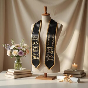 May include: A black graduation sash with gold edging and text. The sash reads "Brown University B.S Class of 2026" on one side and "Software Engineering Belly Green" on the other. The sash is displayed on a mannequin.