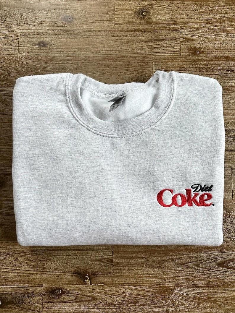 May include: Gray sweatshirt with a red embroidered logo that says "Diet Coke."
