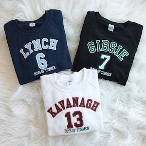 May include: Three navy blue, black, and white sweatshirts with white text and numbers. The text on the sweatshirts reads "Lynch 6 Boys of Tommen", "Gibsie 7 Boys of Tommen", and "Kavanagh 13 Boys of Tommen".