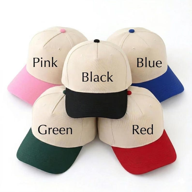May include: Five baseball caps in various colors: pink, black, blue, green, and red. Each cap has a beige crown and a colored brim. The names of the colors are printed on each cap.