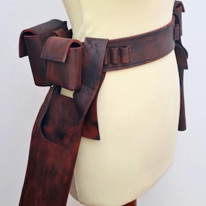 May include: A brown leather holster pattern with multiple pockets and a belt. The pattern is displayed on a white mannequin.