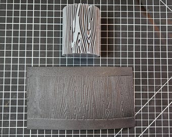 May include: A gray woodgrain textured roller and a black foam sheet with a woodgrain pattern. The roller is used to create a woodgrain effect on surfaces.