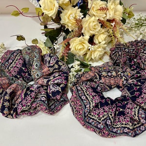 May include: Two dark blue and pink patterned hair scrunchies with floral designs.