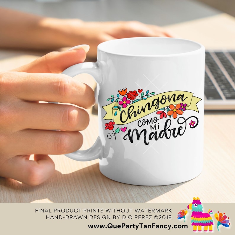 May include: White ceramic coffee mug with a colorful graphic design featuring the text "Chingona Como Mi Madre" in a whimsical font. The design includes flowers and hearts.