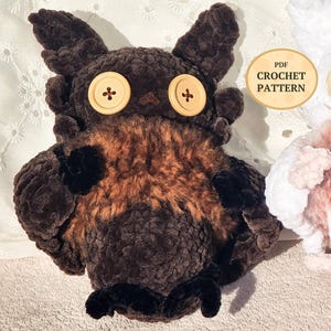 Puede incluir: Un búho de peluche marrón con grandes ojos de botón y un aspecto texturizado y esponjoso. El búho tiene un pecho marrón claro y detalles negros en las alas y los pies. La imagen incluye una superposición de texto que dice "PDF CROCHET PATTERN".