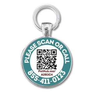 Puede incluir: Una chapa redonda plateada para mascotas con borde turquesa y centro blanco. La chapa presenta un código QR y el texto "PLEASE SCAN OR CALL", junto con un número de teléfono y una dirección web.