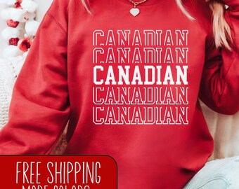 May include: Red sweatshirt with the word "CANADIAN" repeated five times in white text. The sweatshirt is being worn by a person. The text is in a bold, blocky font.