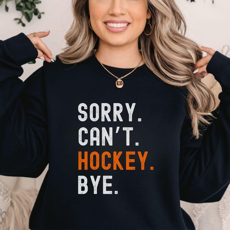 May include: Black sweatshirt with the text "SORRY. CAN'T. HOCKEY. BYE." in white and orange lettering.