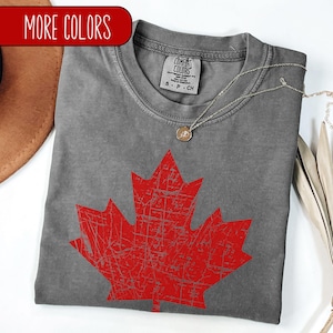 May include: Gray t-shirt with a red distressed Canadian maple leaf design. The shirt has a tag that reads "Comfort Colors" and "S - P - CH".