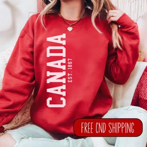 May include: Red sweatshirt with white text that reads "CANADA EST. 1867".