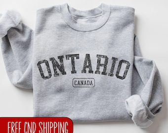 Puede incluir: Sudadera gris con un gráfico de estilo vintage que dice "ONTARIO CANADA" en negro.