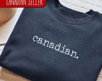 May include: A black sweatshirt with the word "canadian." printed in white on the front.