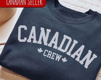 May include: A dark blue sweatshirt with white text that reads "CANADIAN CREW" with a maple leaf on either side of the word "CREW".