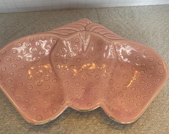 Op de afbeelding: Een roze keramische schaal in de vorm van drie aardbeien. De schaal heeft een getextureerd oppervlak met kleine cirkels.