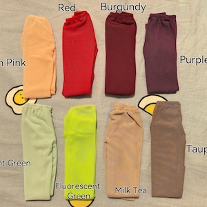 Op de afbeelding: Tien paar leggings in verschillende kleuren, waaronder rood, bordeauxrood, paars, huidskleur roze, mintgroen, fluorescerend groen, melktea en taupe.