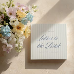 May include: A square book with vertical striped cover, titled "Letters to the Bride" in a script font. The book is next to a bouquet of pastel-colored flowers, including pink, yellow, and blue blooms. The text "DEAR CHELSEA" and "FUTURE MRS BRIGGLEWORTH" are also visible.