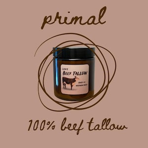 May include: A brown glass jar candle with a black lid. The label reads "Lean's Beef Tallow, Grass-Fed, Wisconsin Dairy". The jar is surrounded by a brown circle with a cow illustration. The text "primal" is above the jar and "100% beef tallow" is below the jar.