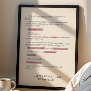 May include: A framed print with text from a novel, featuring highlighted phrases in pink. The print is propped against a wall, next to a bed with gray bedding. A coffee cup and books are in the foreground.