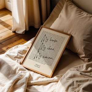 Puede incluir: Una impresi&oacute;n enmarcada con las palabras "My house. My chair. My woman." en una fuente manuscrita. La impresi&oacute;n est&aacute; en un marco de madera clara y descansa sobre una cama con ropa de cama beige. El texto "Chapter 48 Iron Flame" est&aacute; en la parte inferior.