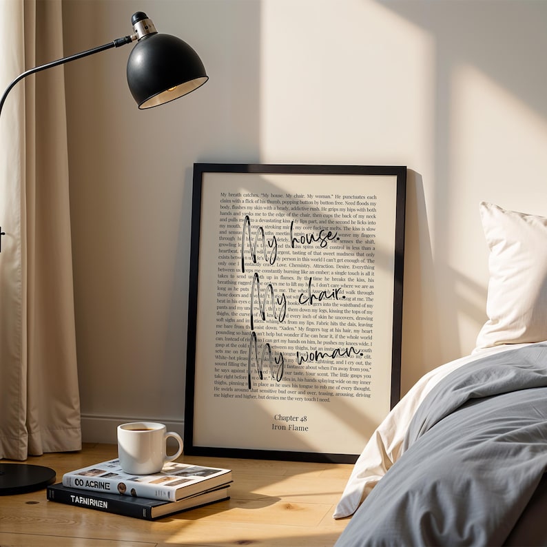 Puede incluir: Una impresi&oacute;n enmarcada con el texto "My house, my chair, my woman" en un estilo manuscrito. La impresi&oacute;n est&aacute; en un marco negro y est&aacute; apoyada contra una pared. Una l&aacute;mpara negra y una pila de libros con una taza de caf&eacute; est&aacute;n en primer plano.