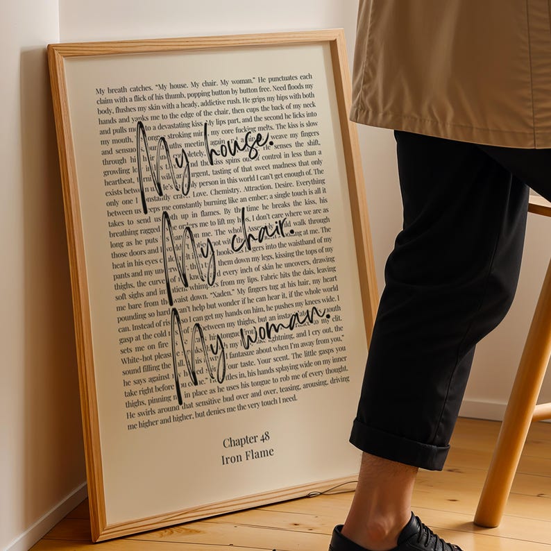 Puede incluir: Una impresi&oacute;n enmarcada con texto del "Cap&iacute;tulo 48 Iron Flame" se muestra. Las palabras "My house. My chair. My woman." est&aacute;n escritas en cursiva. La impresi&oacute;n tiene un marco de madera y est&aacute; sobre un fondo neutro.