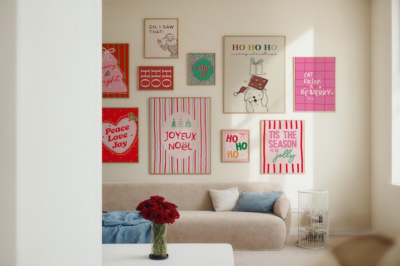 May include: A collection of framed Christmas-themed art pieces displayed on a wall above a beige sofa. The art features festive phrases like "Peace Love Joy", "Joyuex Noel", and "Tis the Season to be Jolly". The room is decorated in a modern style.
