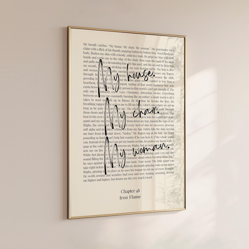 Puede incluir: Una impresi&oacute;n enmarcada con borde dorado presenta una p&aacute;gina de libro con las palabras "My house. My chair. My woman." en una fuente manuscrita. El texto "Chapter 48 Iron Flame" est&aacute; en la parte inferior.