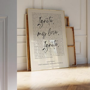 May include: A framed print with the words "Ignite my love Ignite" in a handwritten style. The print has a vintage aesthetic with a cream-colored background and black text. The text is from Aaron Warner, Chief Commander and Regent of Sector 45.