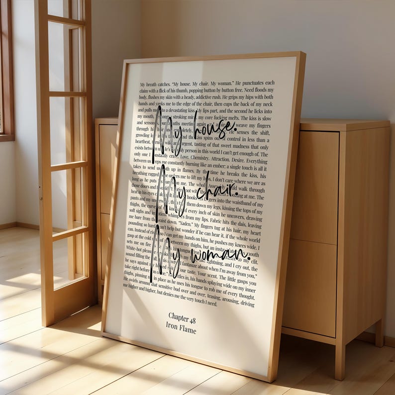 Puede incluir: Una impresi&oacute;n enmarcada con el texto manuscrito "My house. My chair. My woman." y texto del cap&iacute;tulo 48 de "Iron Flame". El marco es de color marr&oacute;n claro. La impresi&oacute;n se muestra en interiores.