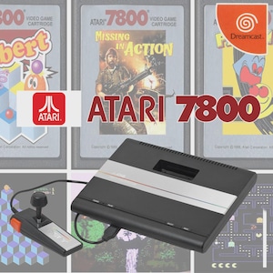 May include: A black Atari 7800 video game console with a silver stripe, connected to a joystick. Game cartridges with the Atari logo and the text "ATARI 7800" are visible, along with a Dreamcast logo.